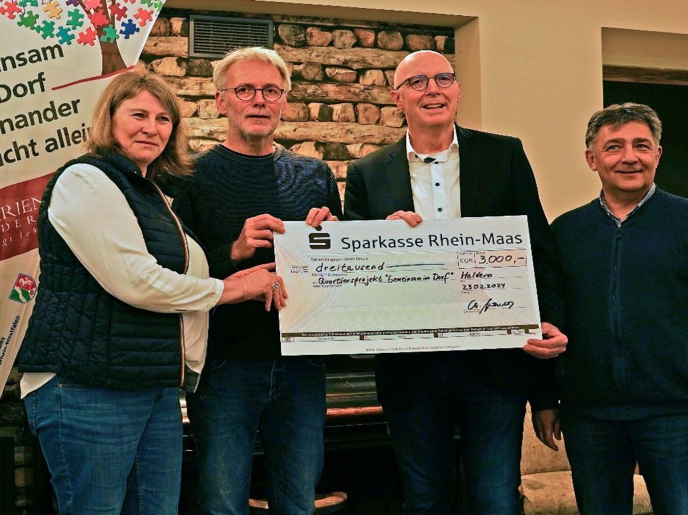 Der Präsident des Lions-Club Emmerich-Rees, Christoph Gerwers (2. v. r.), und Lions-Vorstandsmitglied Dr. Stefan Dahms (r.) überreichen den beiden Quartiersmanagern des Dorfprojektes, Veronika Blume und Kajo Verbeet, einen Scheck über 3.000 Euro. Foto: privat