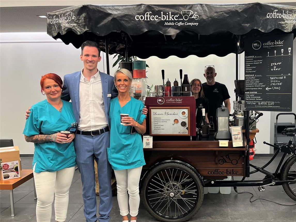 Der stellvertretende Pflegedirektor des St.-Clemens-Hospitals Geldern, Samuel Huhn (Mitte), zusammen mit den beiden Pflegefachkräften der Zentralen Notaufnahme (ZNA) Tanja Breuer (links) und Lena Blaschkowitz (r.) sowie die beiden Mitarbeitenden des Kaffee-Bikes.Foto: St.-Clemens-Hospital