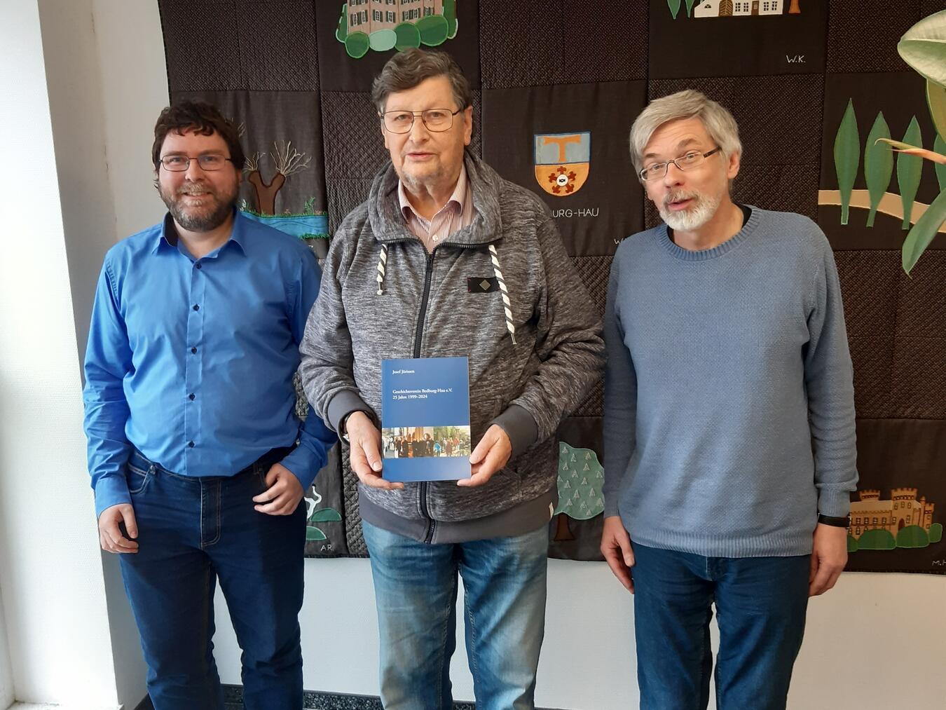 Chronik zum Jubiläum Der stellvertretende Vorsitzende Josef Jörissen (Mitte) bei der Vorstellung der Chronik des Geschichtsvereins im Rathaus Bedburg-Haumit dem neuen Geschäftsführer des Vereins und Archivar der Gemeinde Bedburg-Hau, Tobias Tenhaef (l.),und dem Schriftführer und ehemaligen Geschäftsführer und scheidenden Gemeindearchivar Johannes Stinner (r.). Foto: Geschichtsverein