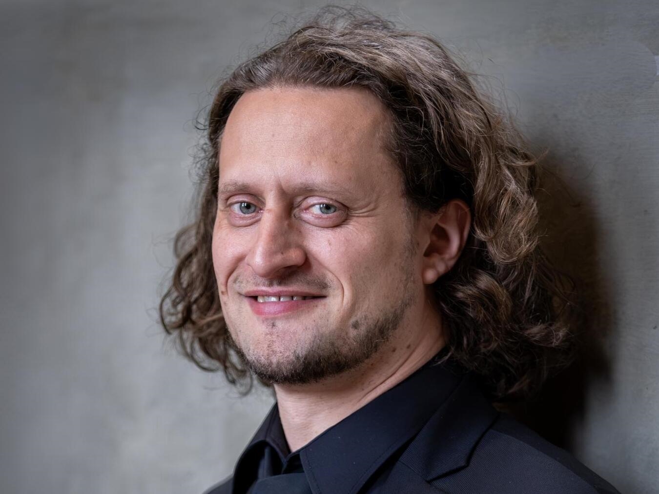 "Tenor Peter Winking lächelnd im Anzug, klassischer Sänger bei Konzertauftritt"