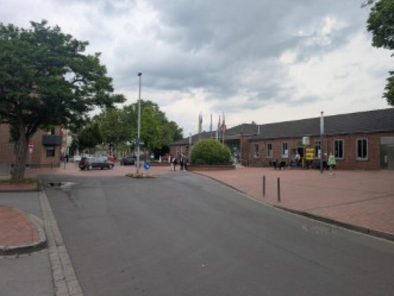 "Verkehrssituation am Bahnhof: dichte Autoschlange und Passanten bei bewölktem Wetter"