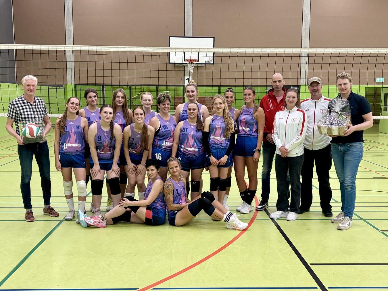 "Damen-Volleyballmannschaft TV Rees in neuen Trikots mit Sponsor Ulrich Biermann, ehemaliger Spieler, bei Teamfoto."