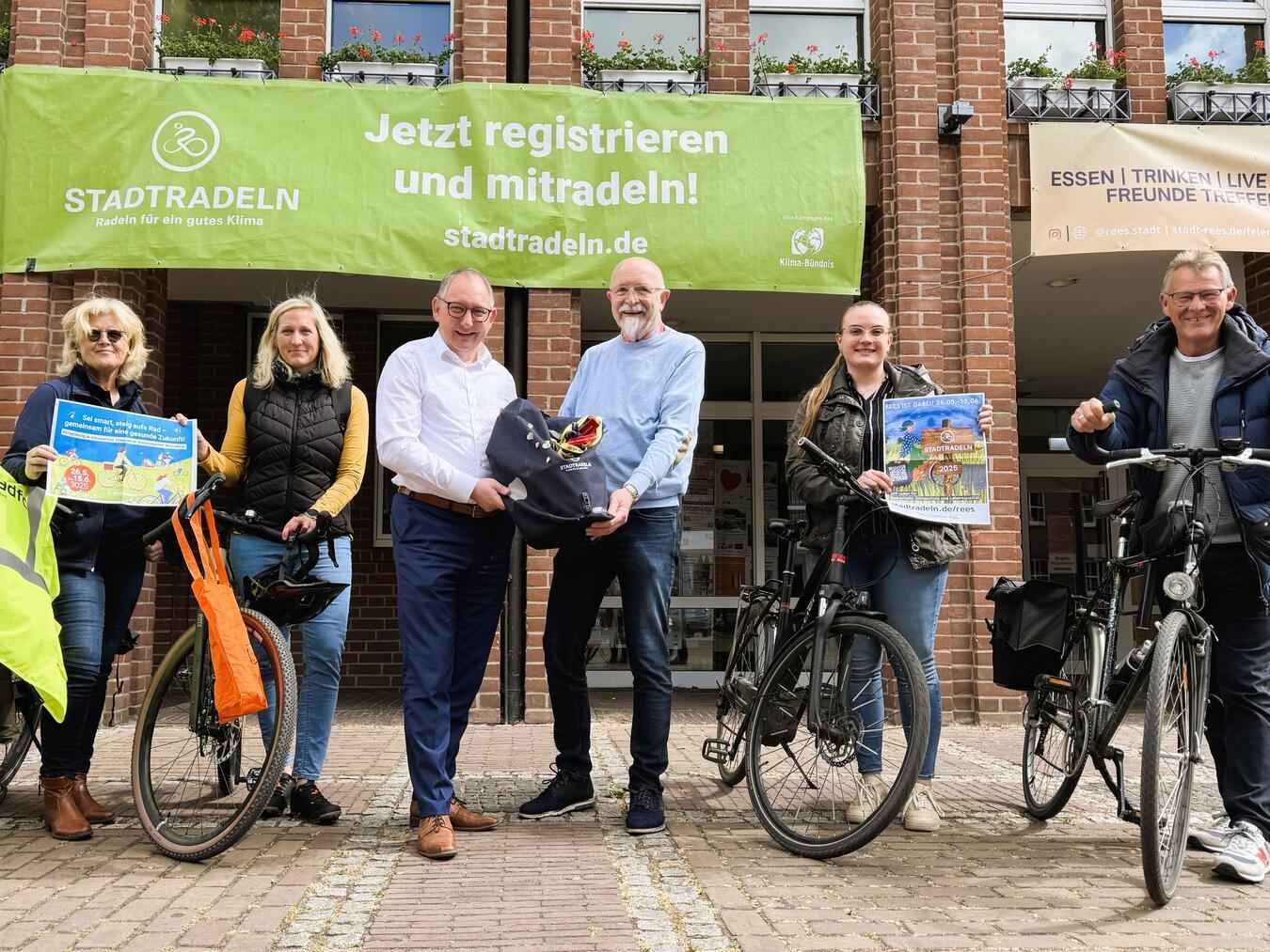 Die Emmericher Delegation bestehend aus Yvonne Surink, Regina Pommerin, Gerhard Gertsen und Celine Breuer übergibt die Staffeltasche an den Reeser Bürgermeister Sebastain Hense (Mitte) sowie den Fahrradbeauftragten Georg Messing (rechts). Foto: Stadt Emmerich