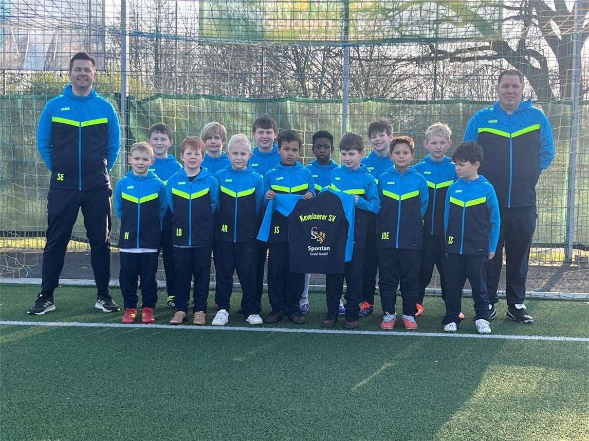 F3-Jugend des Kevelaerer SV in neuen Trainingsanzügen lächelnd auf dem Fußballplatz.