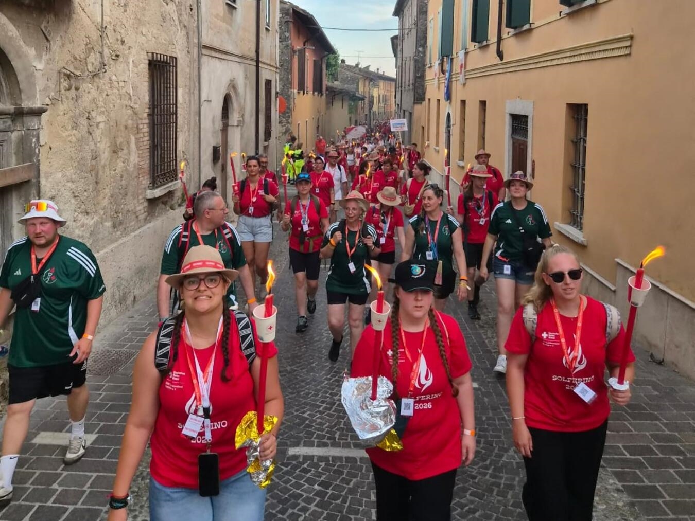 "Fiaccolata 2023: Menschenmenge mit Fackeln auf historischer Route Solferino-Castiglione, Delegation aus Goch beeindruckt."