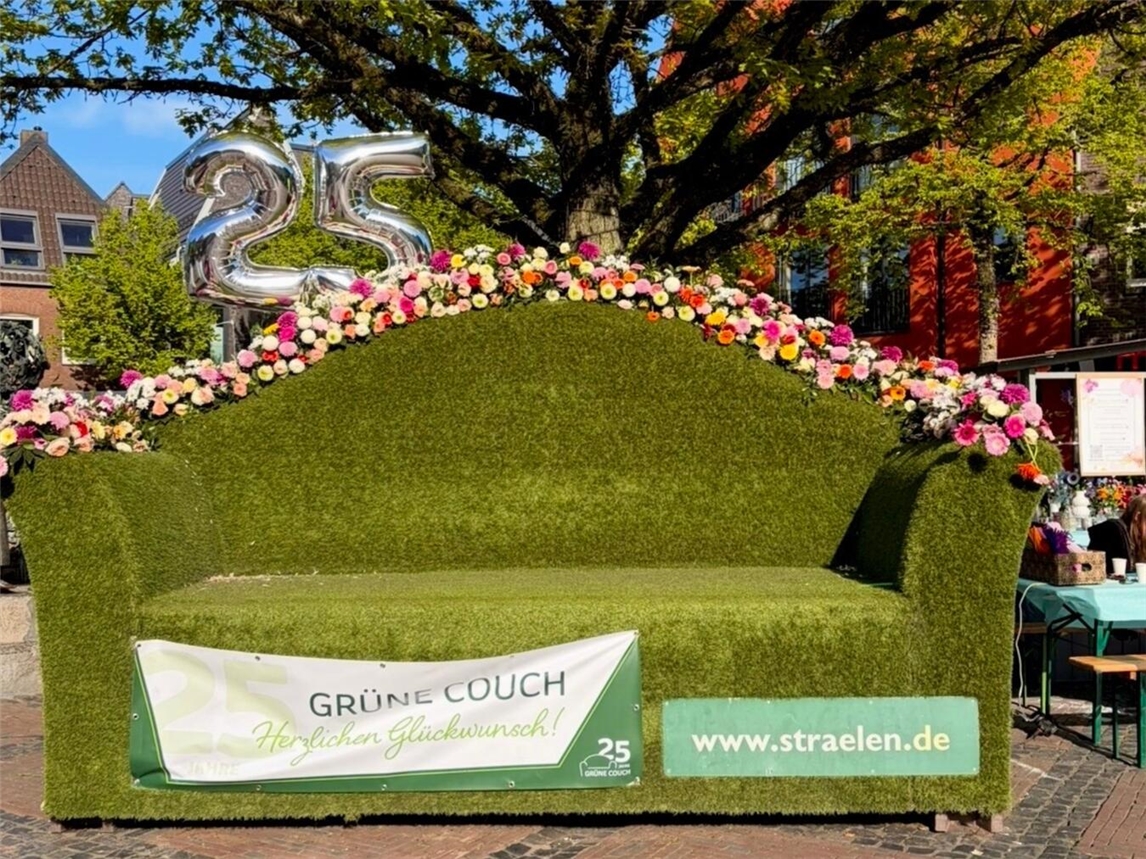 Grüne Couch auf Frühlingsblumenmarkt 2026, Straelen, umgeben von bunten Blumenarrangements.