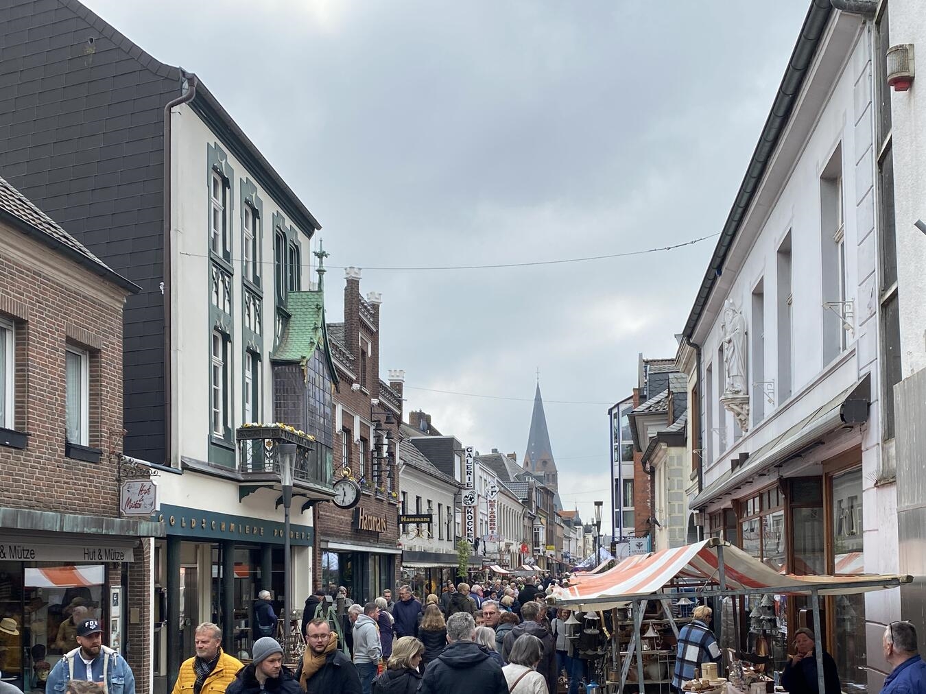 "Lebhafte Hauptstraße in Kevelaer mit Geschäften und Passanten, Stadtansicht am Tag"