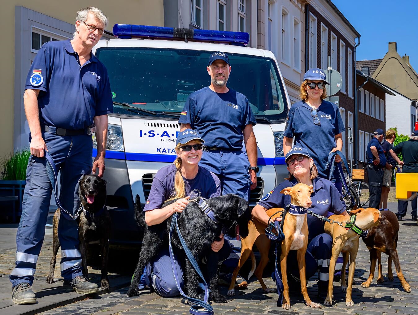 Hundeführer und Hunde aus Keppeln, Bedburg-Hau, Materborn, Pfalzdorf auf Wiese versammelt. Foto von Kathleen Hocevar.