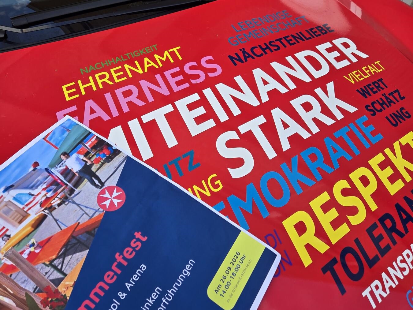 Johanniter Emmerich werben mit Plakat auf Motorhaube für ihr Sommerfest.