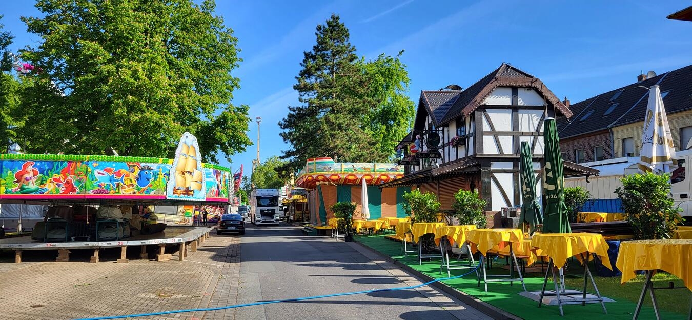 Großeinsatz für die Kirmes: Aufbau läuft auf Hochtouren "Farbenfrohe Kirmesmeile im Aufbau bei Nacht, beleuchtet mit Fahrgeschäften und Lichtern, fotografiert von Michael Bühs"