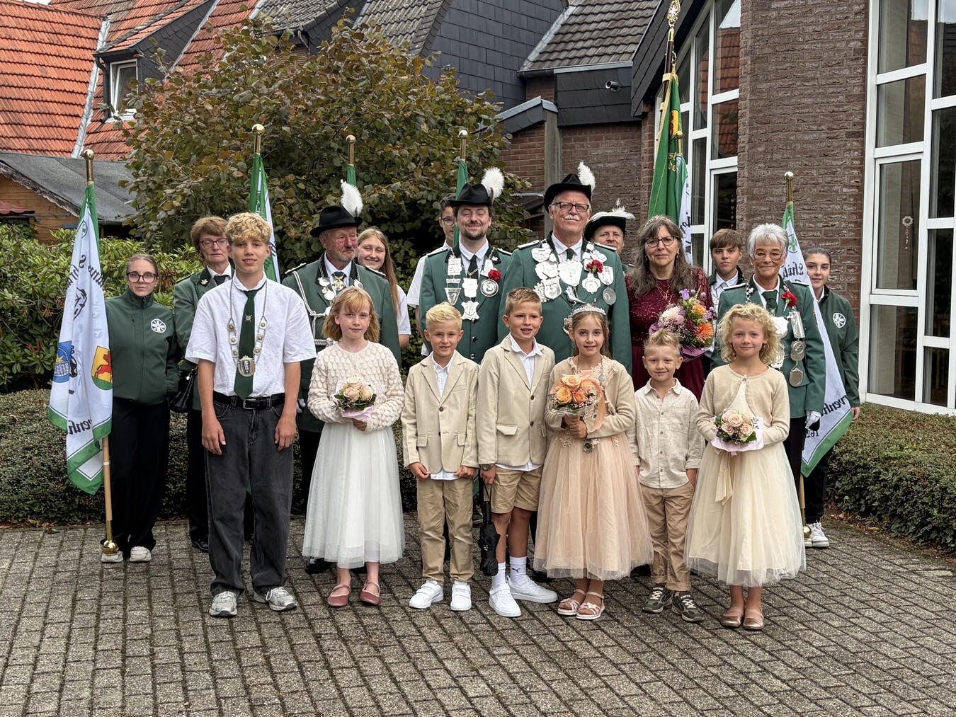 "Neue Majestäten am katholischen Pfarrheim Kervenheim, festlich gekleidet, Gruppenfoto vor historischer Kulisse."