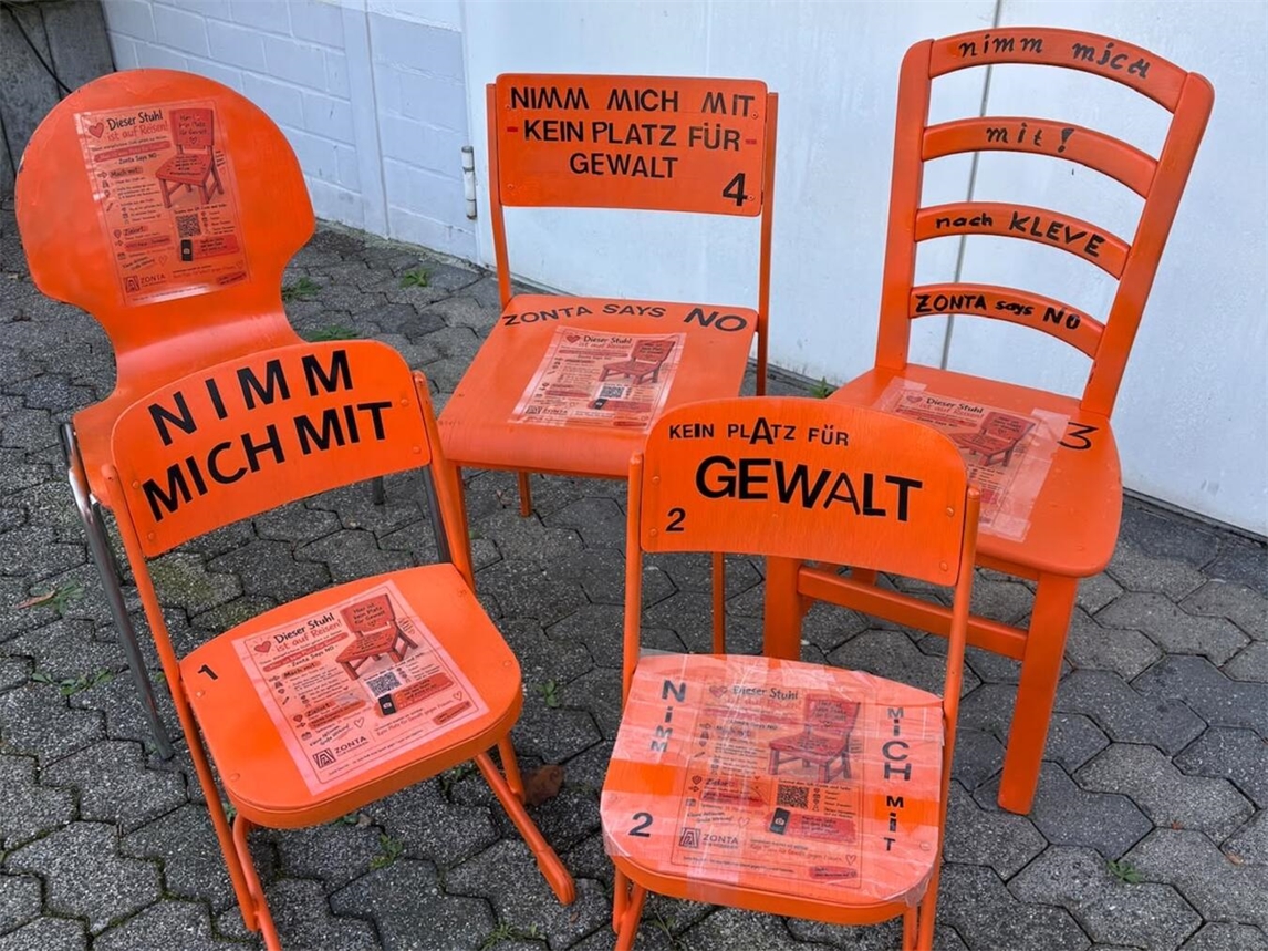 "Orangefarbene Stühle auf Reisen, Zonta Club Niederrhein, symbolisieren Mobilität und Gemeinschaft"