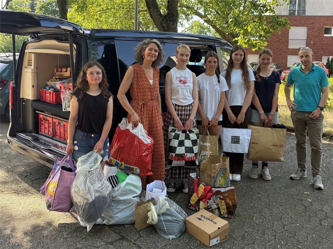 Projektinitiatorinnen und Team freuen sich über Spenden mit Schulleiter, unterstützt von Religionslehrerin und Klassenkameraden.