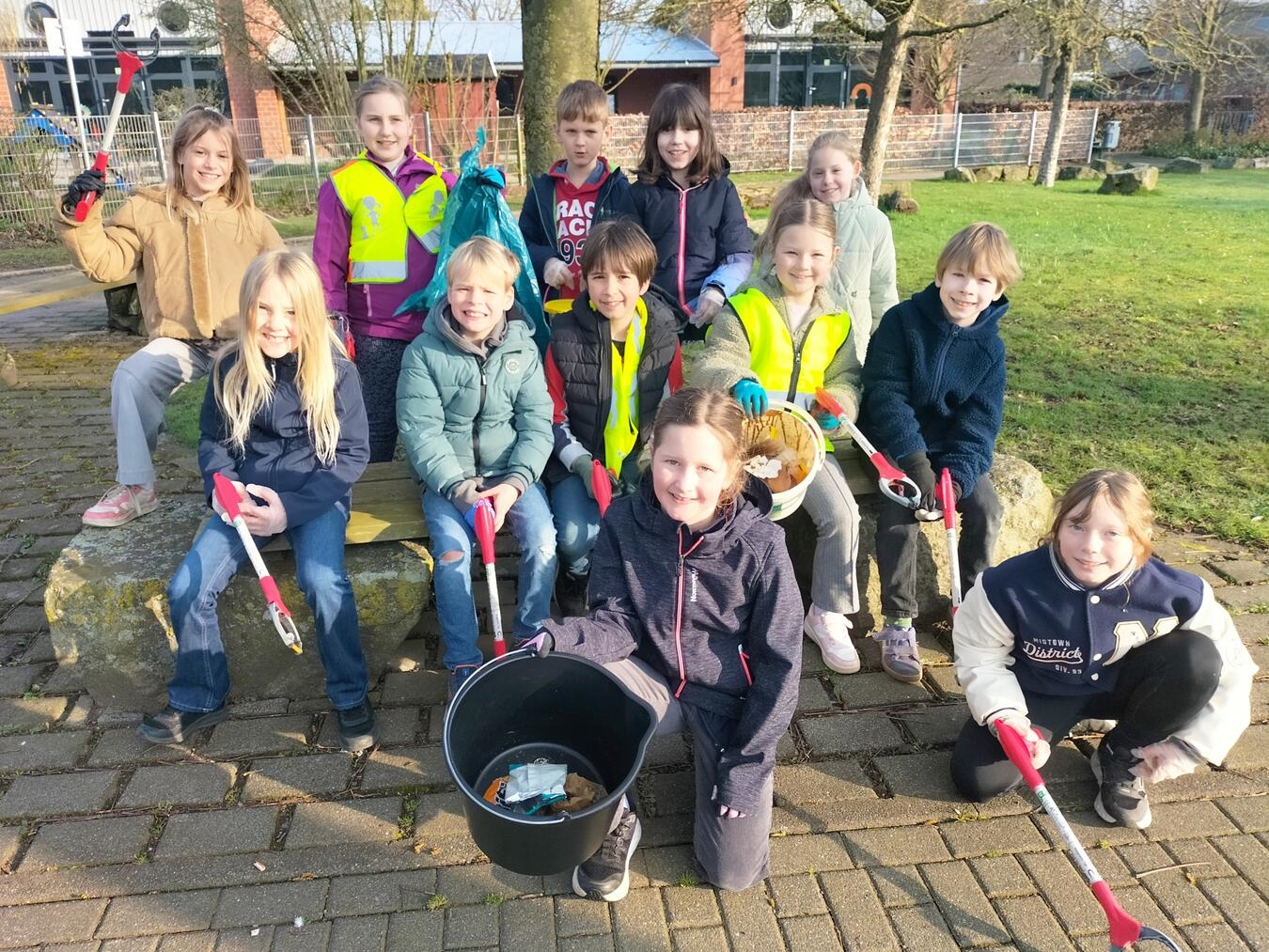 Kinder mit Müllsammelzangen und Mülleimern bei der Müllsammelaktion in Hartefeld