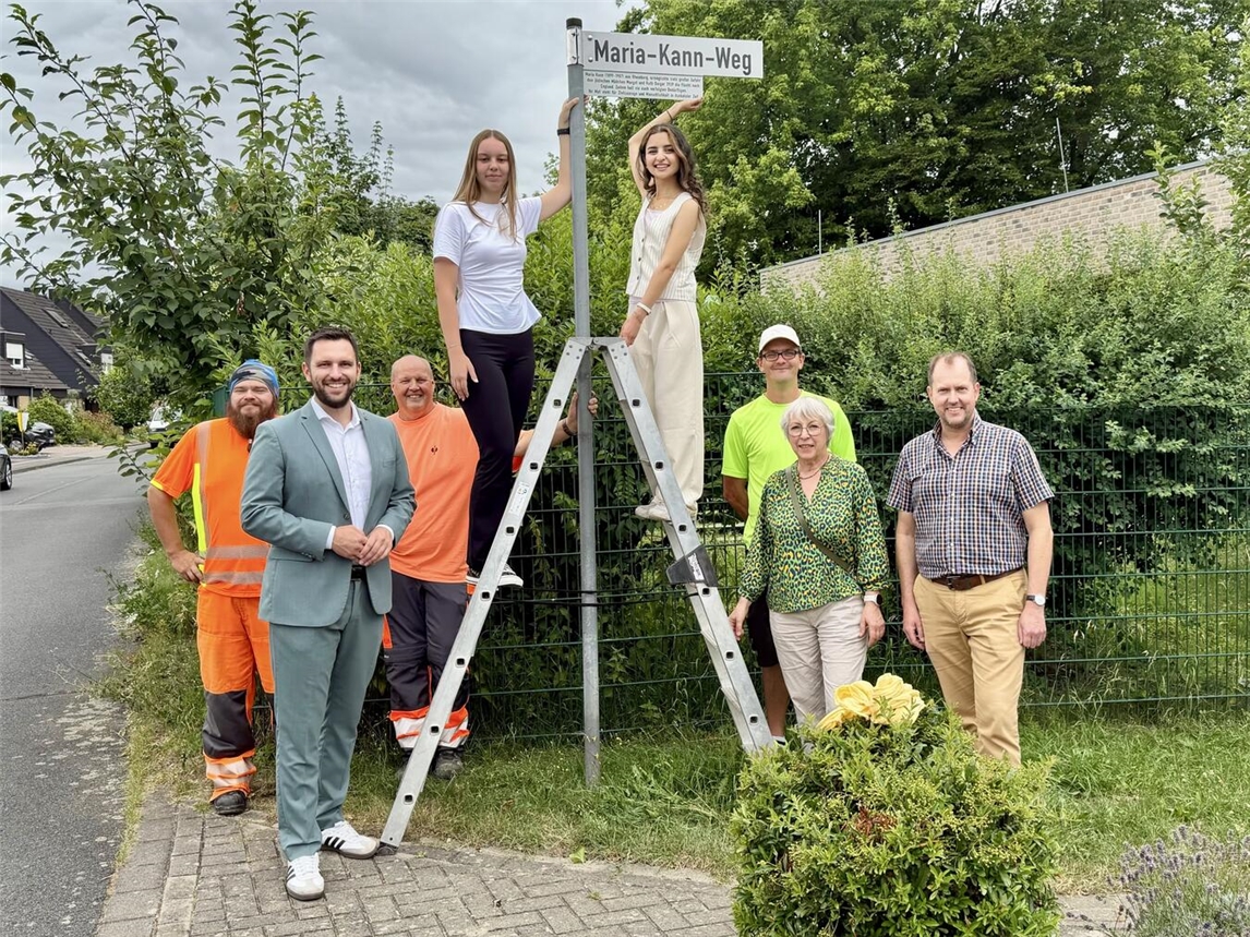 Nadja Gerten und Afrah Girdo montieren Schild mit Stadtvertretern in Rheinberg.