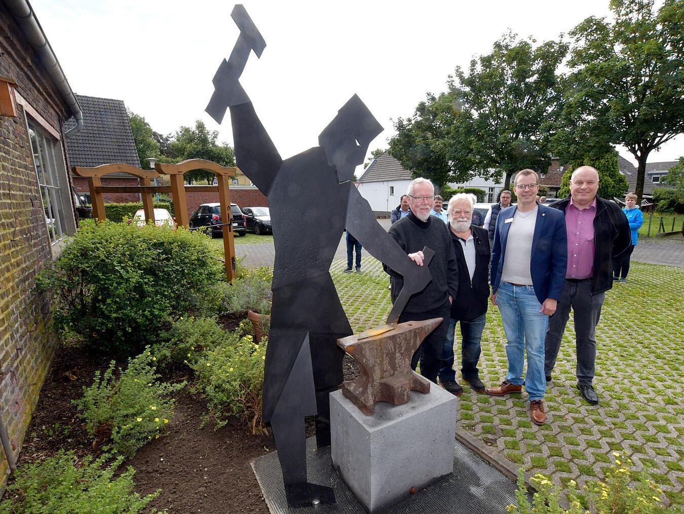 Die Skulptur „Schmied“ ziert jetzt die Dorfmitte. Das freut (v.l.) Künstler Wolfgang Frische, Stifter Willy Goebels, Bürgermeister Stephan Reinders und Hans-Peter Linzen. NN-Foto: Rüdiger Dehnen