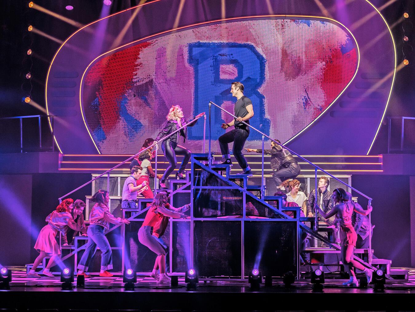 Die spannende Neuinszenierung des Musicals katapultiert die Zuschauer in eine Zeit zwischen Petticoats und Lederjacken, schnellen Autos und heißen Partys und erweckt die 50er Jahre zum Leben.