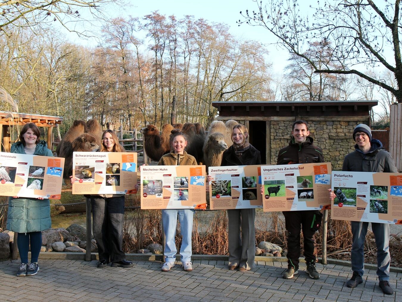Die Studenten sowie die Betreuer (Ramona Kirsch (l.), Axel Huth (r.) und Tiergartenleiter Martin Polotzek (2.v.r.)) präsentieren die neuen Schilder im Tiergarten. Foto: Tiergarten Kleve