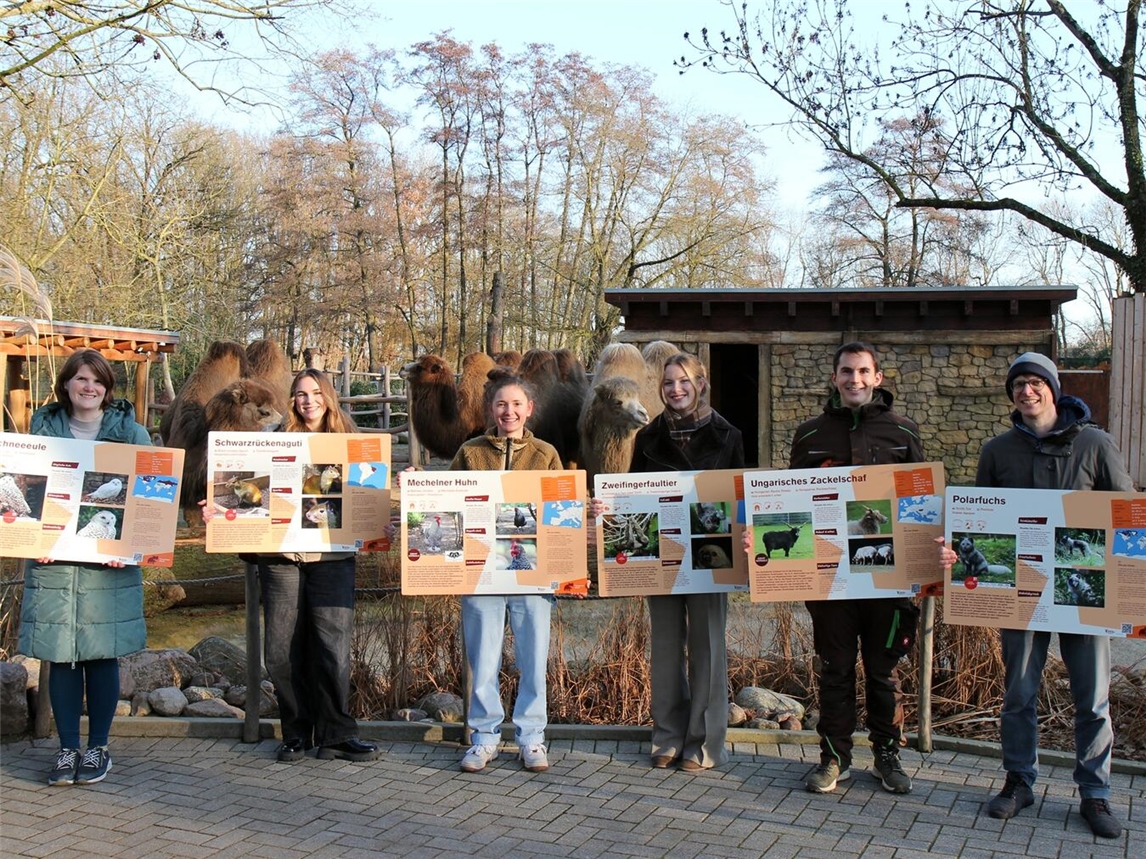 Die Studenten sowie die Betreuer (Ramona Kirsch (l.), Axel Huth (r.) und Tiergartenleiter Martin Polotzek (2.v.r.)) präsentieren die neuen Schilder im Tiergarten. Foto: Tiergarten Kleve