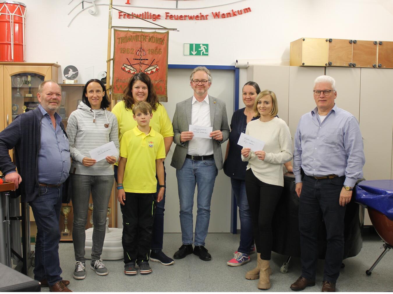 Die symbolische Spendenübergabe fand im Probenheim des Spielmannzuges statt. Das Foto zeigt: Herbert Schmitz (Spielmannszug FF Wankum), Rosi Bloemen (OGS Grundschule Wankum), Martina und Jonas Tomaschek (Kinderchor Wankum), Bürgermeister Paul Hoene (Weihnachtsgeschenke-Aktion Gemeinde Wachtendonk), Svenja Lokotsch und Kim Kalter (Förderverein KIGA Wankum) sowie Eckhard Prewitz (Chorgemeinschaft Wankum/Wachtendonk/Aldekerk).Foto: privat