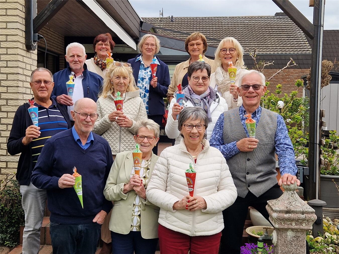 Klassentreffen der Jahrgangsstufe mit Teilnehmern in drei Reihen, lächelnd und entspannt; Gruppenfoto, nostalgische Atmosphäre.