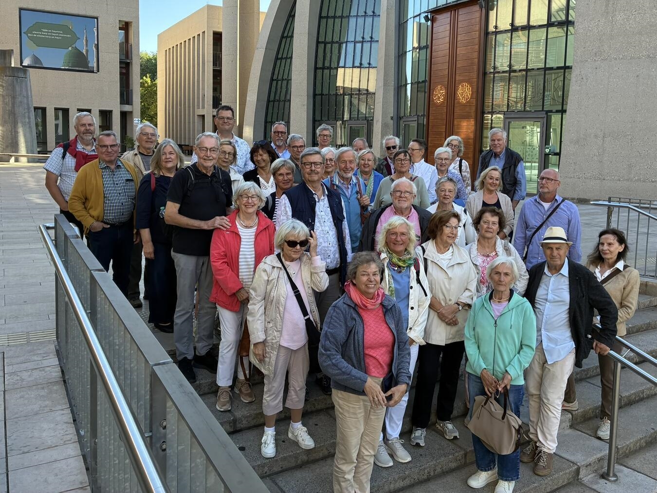 "Gruppe von Teilnehmern vor der Kölner Moschee bei sonnigem Wetter"