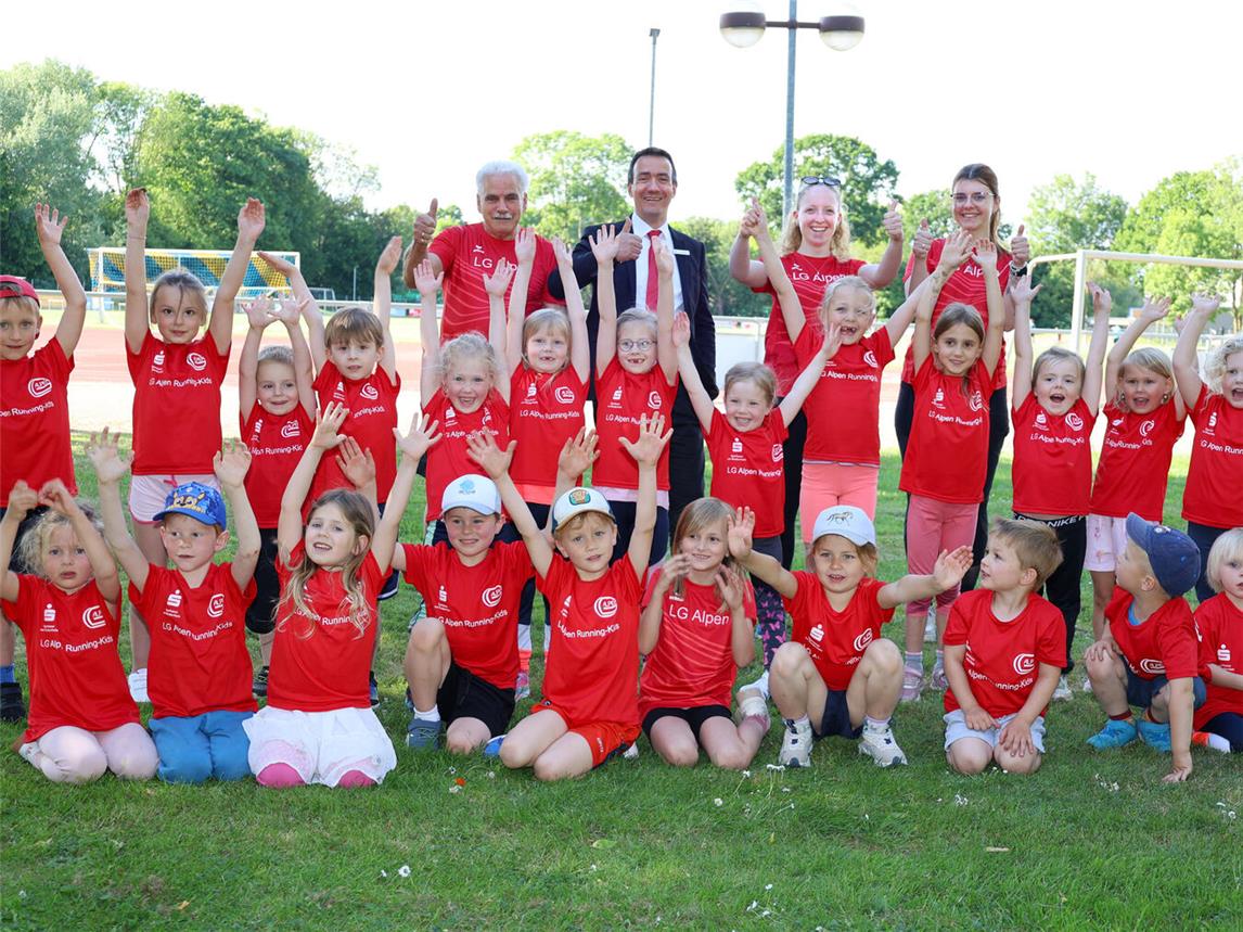 Die vier- bis siebenjährigen Running-Kids der LG Alpen freuen sich über die neuen Laufshirts. Trainer Wilhelm Schmitz (v.l.n.r.), Tim Rütters von der Sparkasse sowie die Trainerinnen Tadea Opfer und Carolin Stienen finden das topp. Foto: Sparkasse am Niederrhein