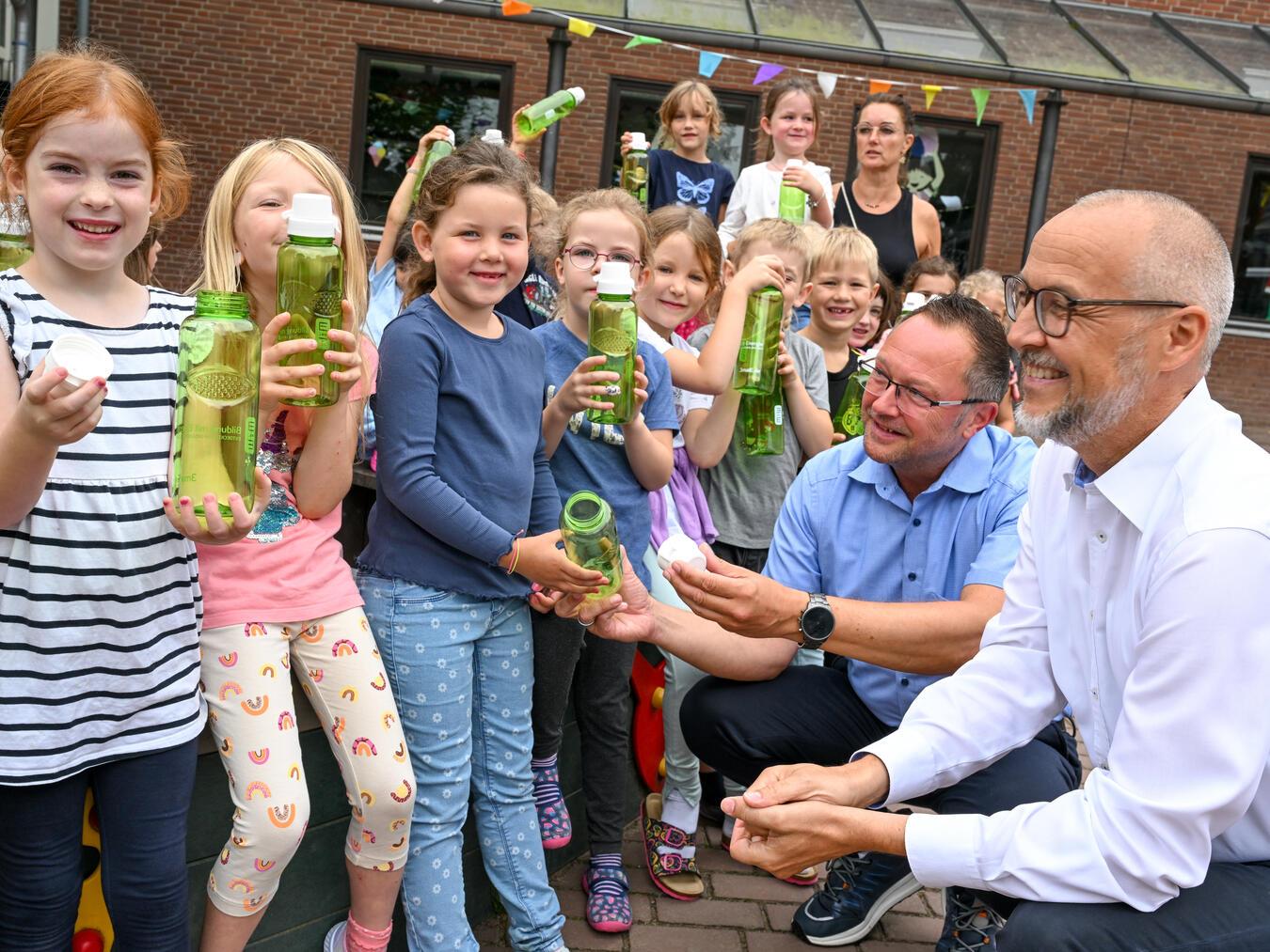 Dirk Krämer (l.), Westenergie-Kommunalmanager, Schulleiterin Daniela Hommen (Mitte.) und Bürgermeister Thomas Görtz (r.) bei der Übergabe der Trinkflaschen an die über 80 Erstklässler. Foto: Westenergie AG