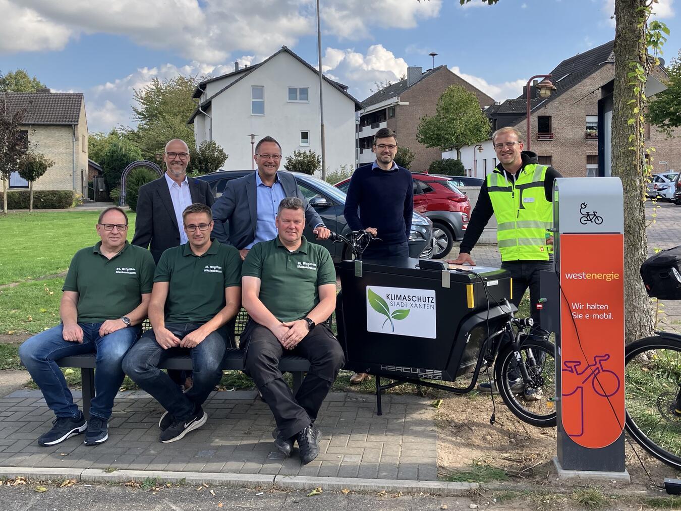 Dirk Krämer, Westenergie-Kommunalmanager, Bürgermeister Thomas Görtz, Stefan Wadleich und Christian Schmitz (hinten v. l. n. r.) sowie Udo Van Loock, Felix Zucke und Stephan Kuypers (vorne v. l. n. r.) von der St. Birgitten Schützenbruderschaft nahmen die eBike-Ladesäule in Betrieb. Foto: Westenergie