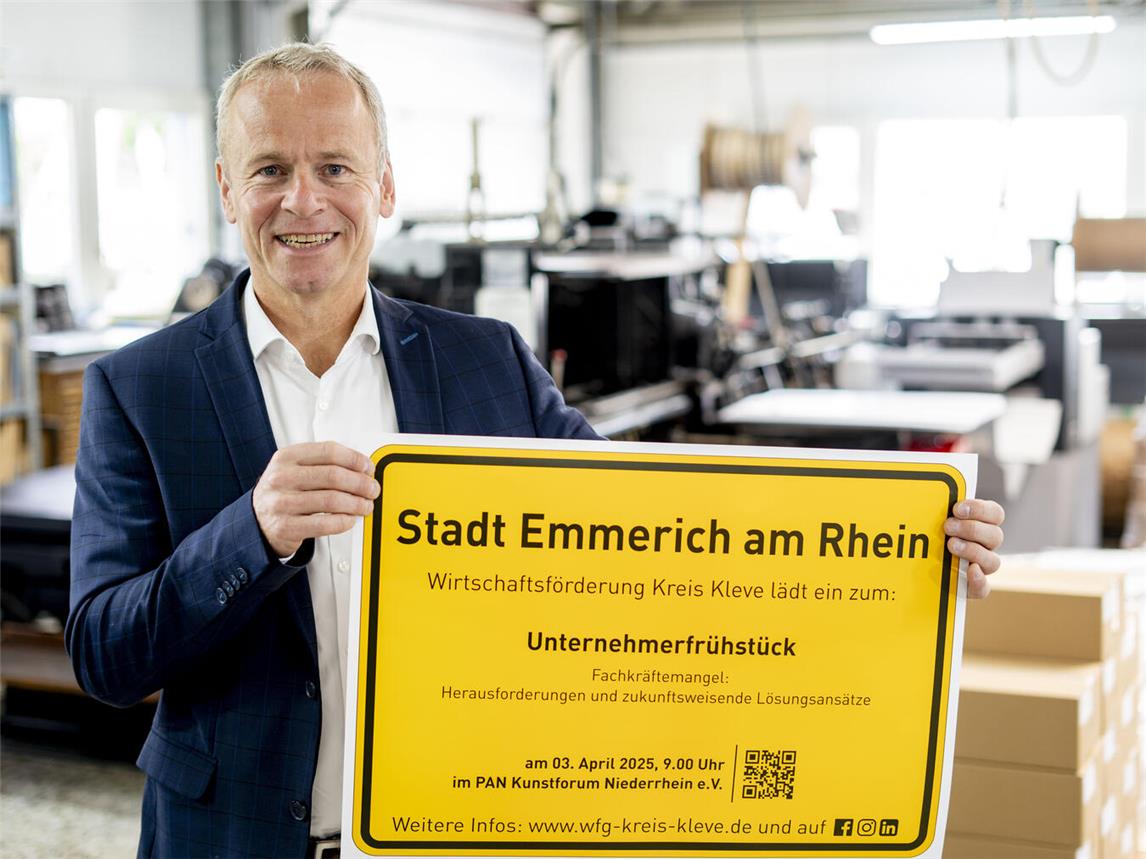 Dr. Benedikt Rösen von der Wirtschaftsförderung Kreis Kleve präsentiert das Ortsschild der Stadt Emmerich mit der Einladung zum Unternehmerfrühstück. Foto: Gerhard Seybert