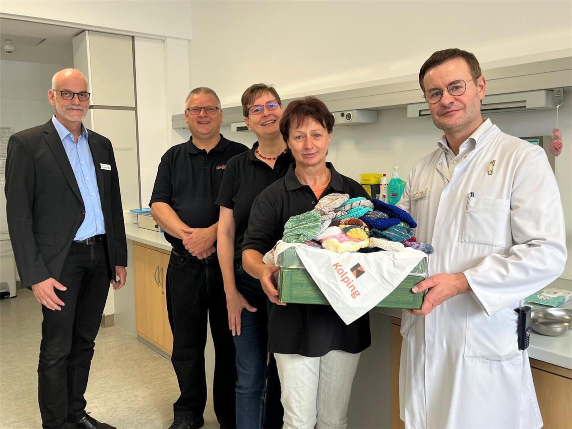Dr. med. Karsten Thiel (r.), Chefarzt der Klinik für Kinder und Jugendliche des St.-Clemens-Hospitals, nimmt gemeinsam mit Ludger Broeckmann (l.), Kaufmännischer Direktor des Gesundheitscampus St.-Clemens Geldern, den vollen Korb mit handgestrickten Mützchen für die Neugeborenen des Gelderner Krankenhauses von Hildegard Schmetter (r.) sowie Silke und Michael Gawellek von der Kolpingsfamilie Geldern entgegen.Foto: St.-Clemens-Hospital