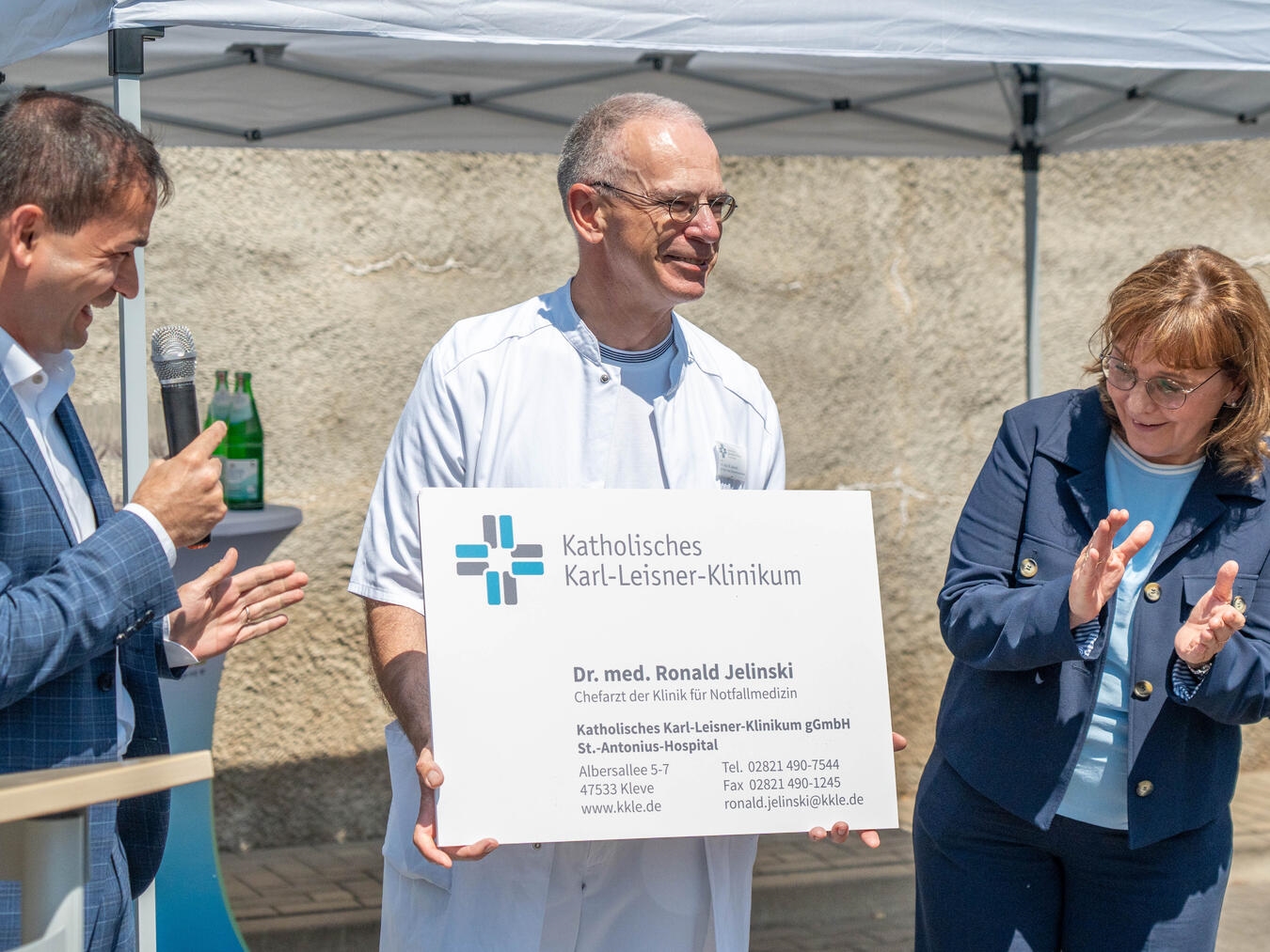 Dr. Ronald Jelinski, neuer Chefarzt der Notfallklinik, mit KKLE-Geschäftsführern und übergroßer Visitenkarte.