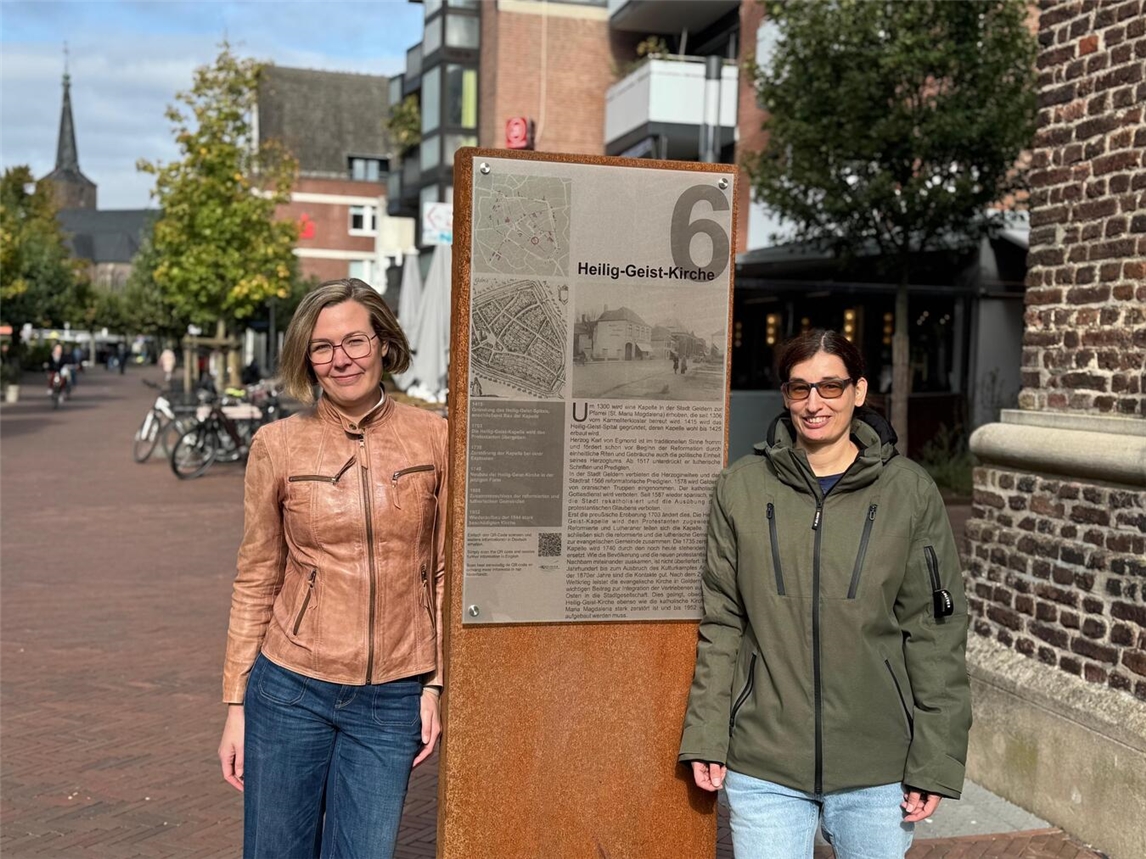 Dr. Yvonne Bergerfurth (l.), Leiterin des Stadtarchivs, und Jessica Wey vom Team Erschließung an der Stele 6 an der Heilig-Geist-Kirche.Foto: Stadt Geldern/Gossens