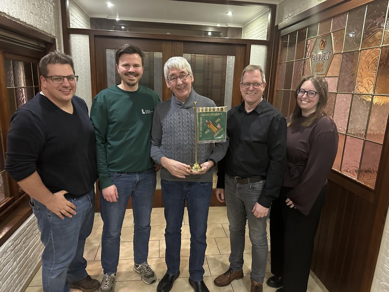 Ein besonderer Moment und ein einzigartiges Geschenk für Charly Vermöhlen (Mitte): Hartefelds Brudermeister Peter Bauer (2.v.r.), sein Stellvertreter Niklas Verhoeven (l.) und Schriftführerin Sarah Friese (r.) überreichten dem scheidenden Kirchenfähnrich eine präzise Nachbildung der Hartefelder Kirchenfahne. Zum Nachfolger an der Kirchenfahne wählten die Schützen Lukas Poschmann (2.v.l.).Foto: hvs