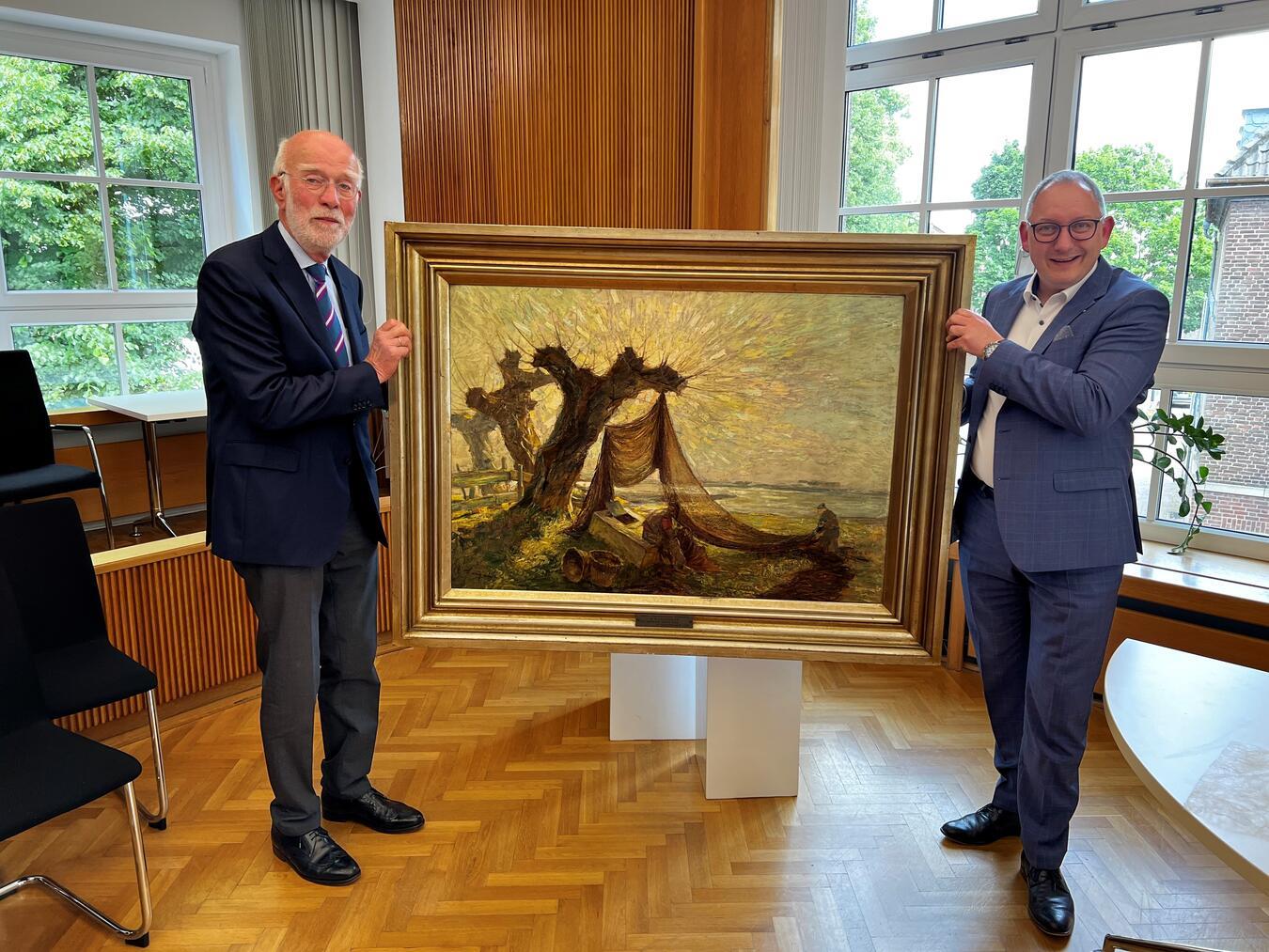Ein Bild mit Stadtgeschichte kommt zurück nach Rees: Franz-Josef Zumnorde (l.) und Bürgermeister Sebastian Hense. Foto: Stadt Rees