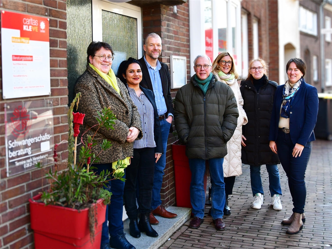 Gruppenfoto vor Caritas-Beratungszentrum Rees: Sechs Caritas-Mitarbeiter und Pfarrer Engels, starkes Netzwerk für Menschen in Not.