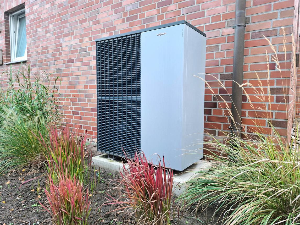 Ein Wärmepumpen-Außengerät vor einem umgerüsteten Bestandsgebäude. Foto: Öko-Zentrum NRW/B. Häming