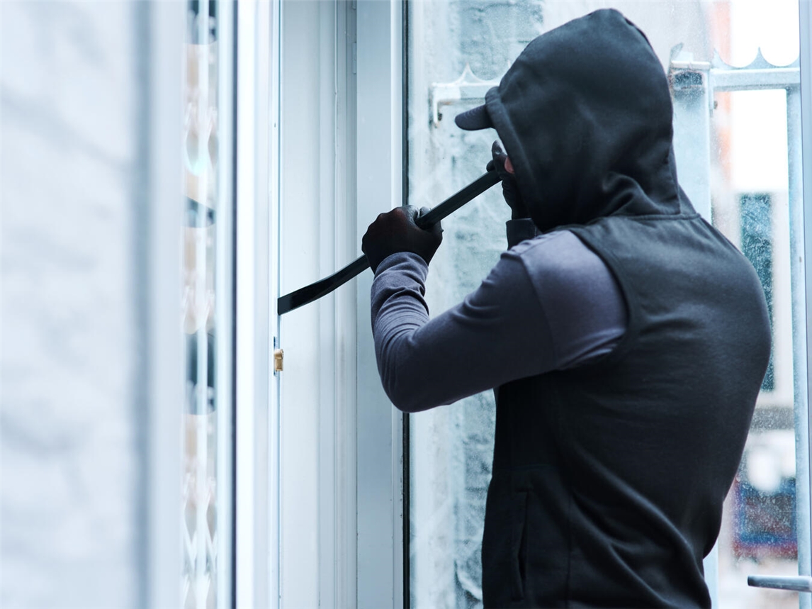 Ein Einbrecher hebelt eine Tür auf