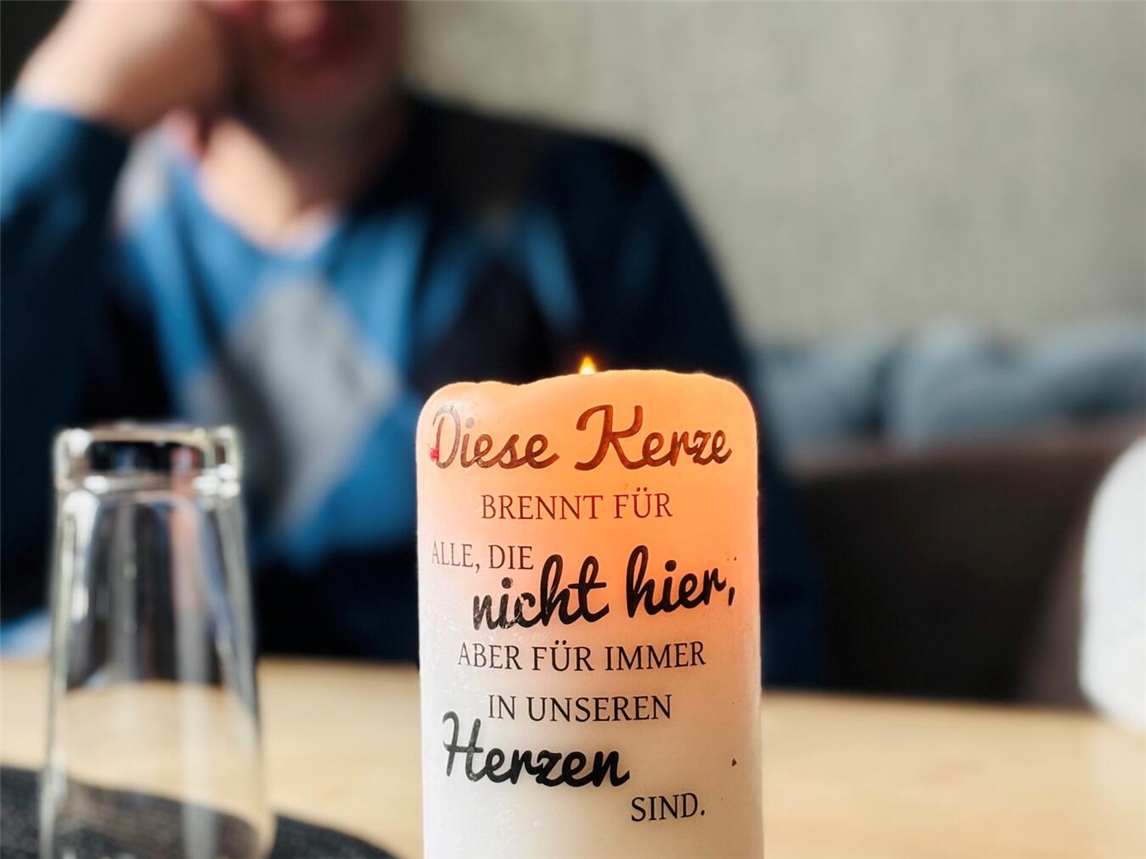 Gedenkkerze bei Nacht für Verstorbene, leuchtend auf schwarzem Hintergrund, Symbol der Erinnerung und Trauer.