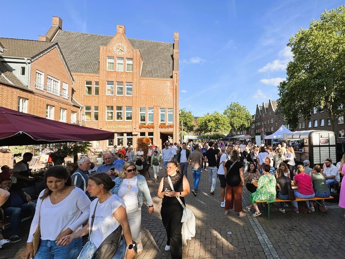 "Reeser Feierabendmarkt 2023: Menschen genießen Essen, Getränke und Gespräche am Abend."