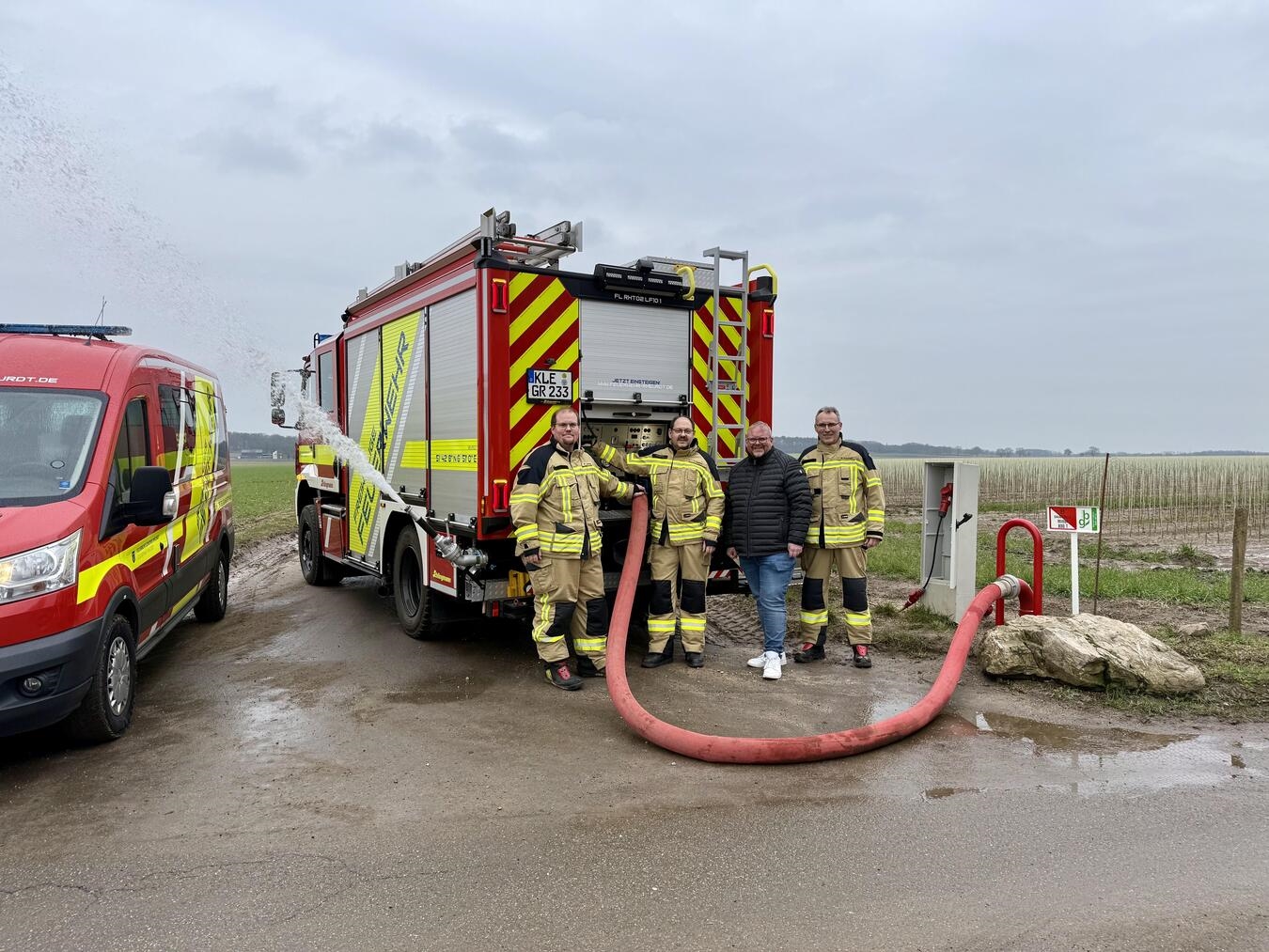 Einer der neuen Löschwasserbrunnen in Saelhuysen im Betrieb, davor eines der beiden neuen Löschfahrzeuge LF10: (v.l.n.r.) Marc Niessing (Löscheinheitsführer Rheurdt), Frank Diepers (Löscheinheitsführer Schaephuysen), Bürgermeister Dirk Ketelaers und Markus Gehrmann (Leiter der Feuerwehr).Foto: Galka