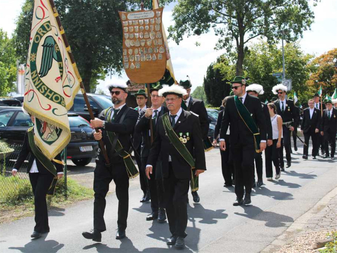 "Traditioneller Schützenumzug mit festlich gekleideten Teilnehmern und dekorierten Fahnen in der Innenstadt."