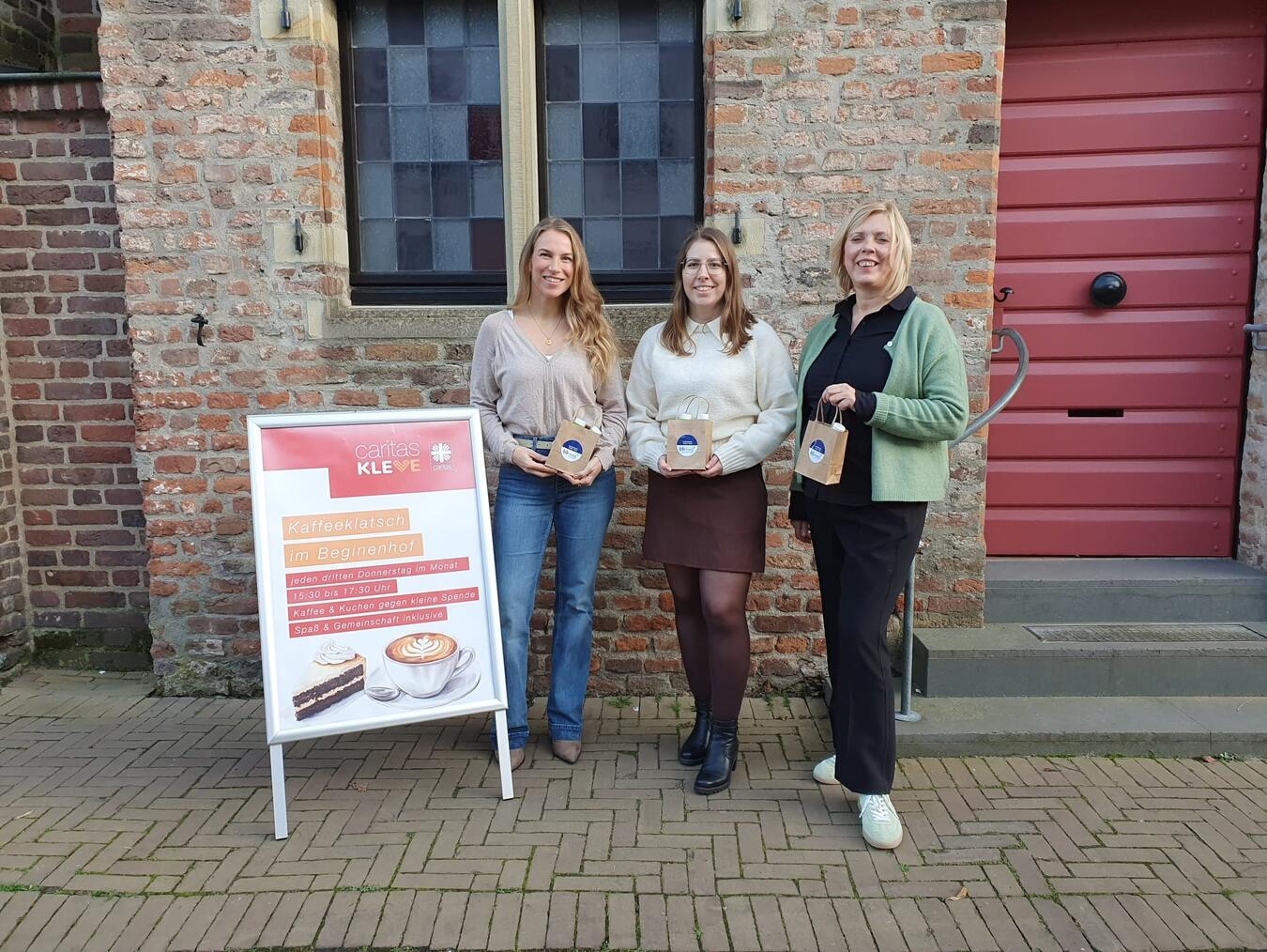 Elke Huber-Groenewald (rechts) nimmt die Geschenktütchen von Sarah Boeckstegers (Mitte) und Anne Unterberg entgegen. Foto: Caritas