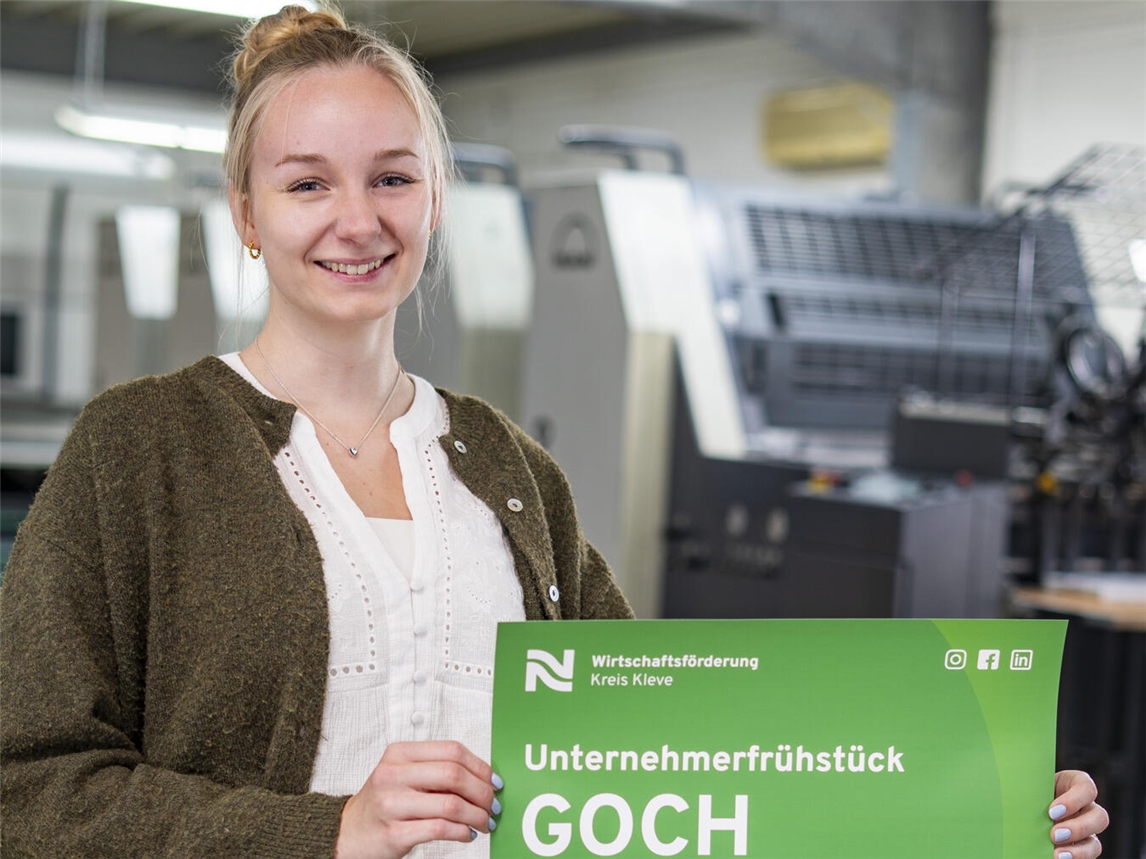 Emma Korn, Werksstudentin bei der Wirtschaftsförderung Kreis Kleve, präsentiert das Plakat mit der Einladung zum Unternehmerfrühstück in Nierswalde.Foto: Gerhard Seybert