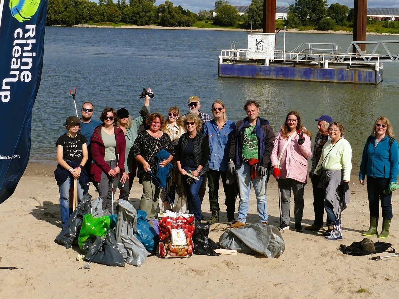 "Geocacher sammeln Zigarettenkippen am Rheinufer für Umweltschutzaktion."
