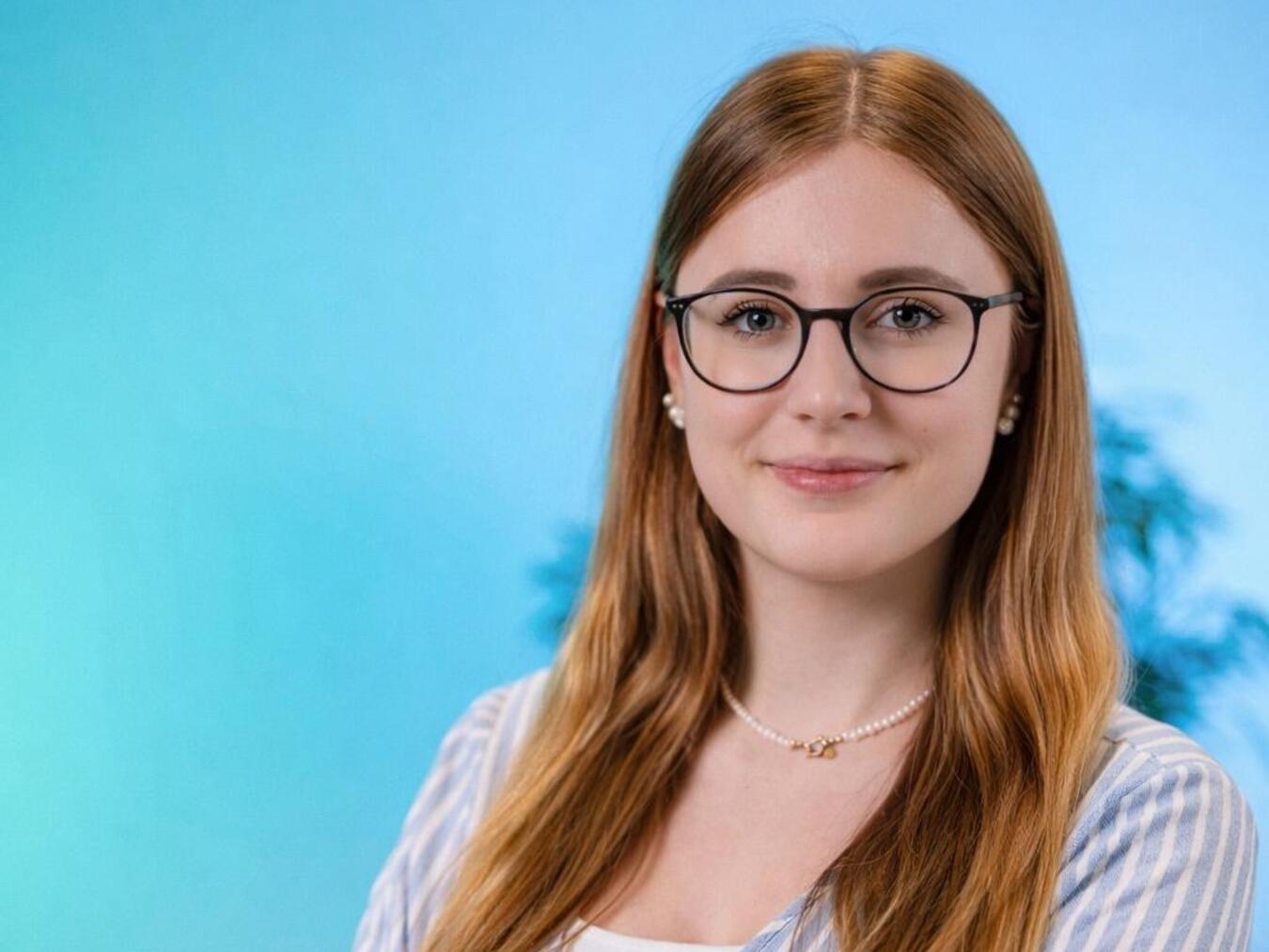 "Erntekönigin Annika Hölker in traditioneller Tracht bei der Erntefeier, lächelnd unter blauem Himmel."