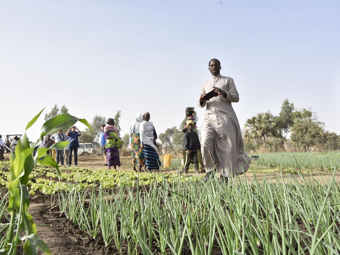 Erzbischof Laurent Lompo besucht eine Frauengruppe, die nahe eines Brunnens nun ein bisschen Landwirtschaft betreiben kann. Foto: privat