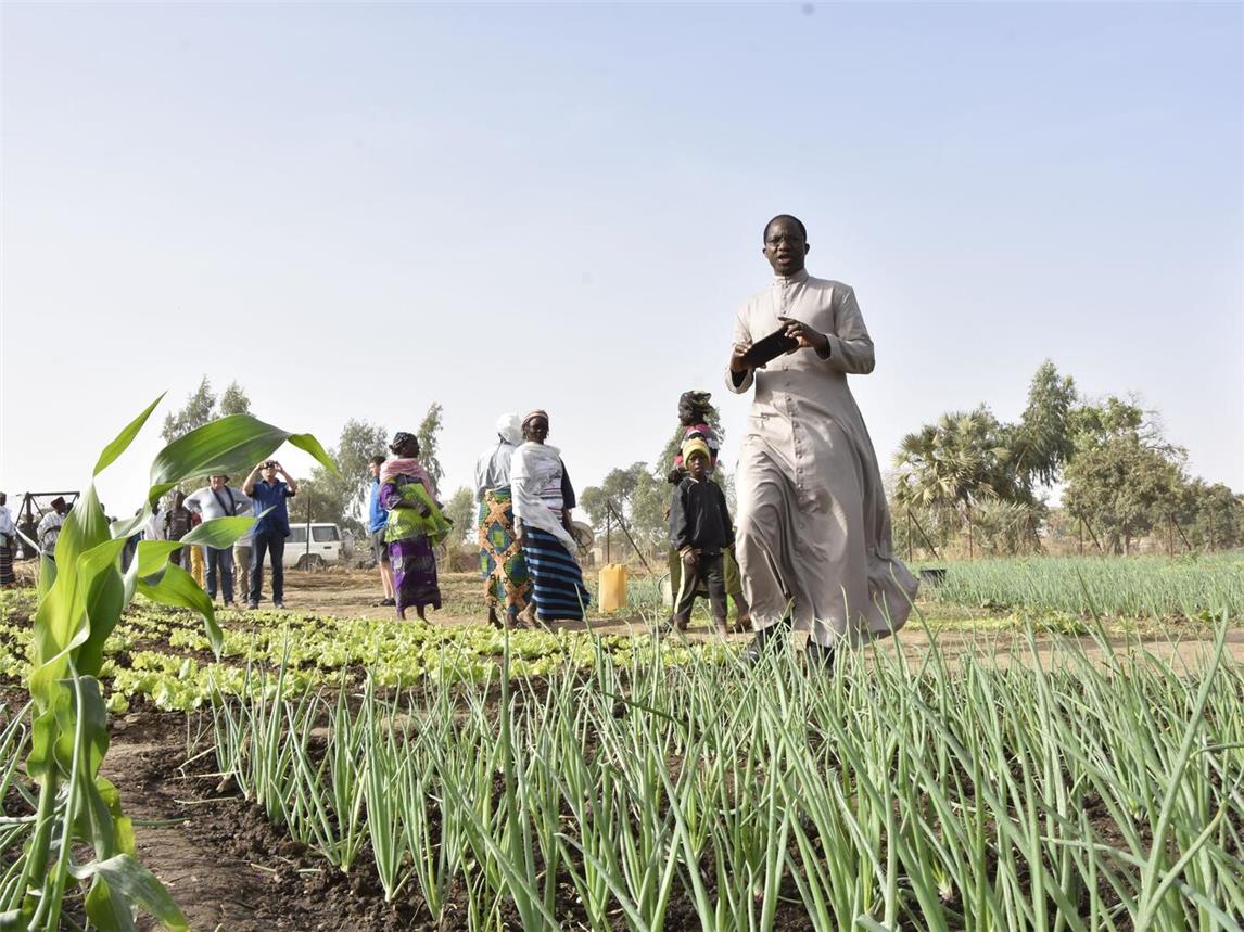 Erzbischof Laurent Lompo besucht eine Frauengruppe, die nahe eines Brunnens nun ein bisschen Landwirtschaft betreiben kann. Foto: privat
