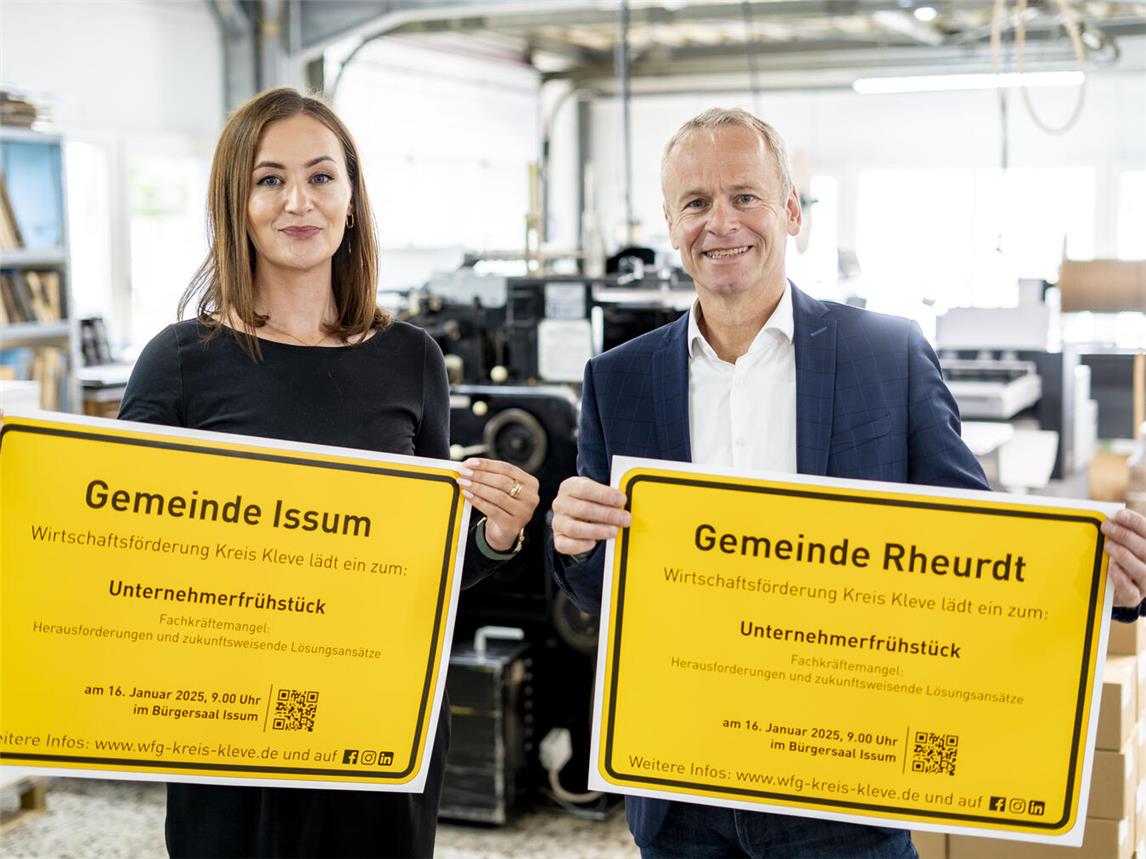 Fee Knupp und Dr. Benedikt Rösen von der Wirtschaftsförderung Kreis Kleve präsentieren die Ortsschilder der Gemeinden Issum und Rheurdt mit der Einladung zum Unternehmerfrühstück.Foto: WfG Kreis Kleve