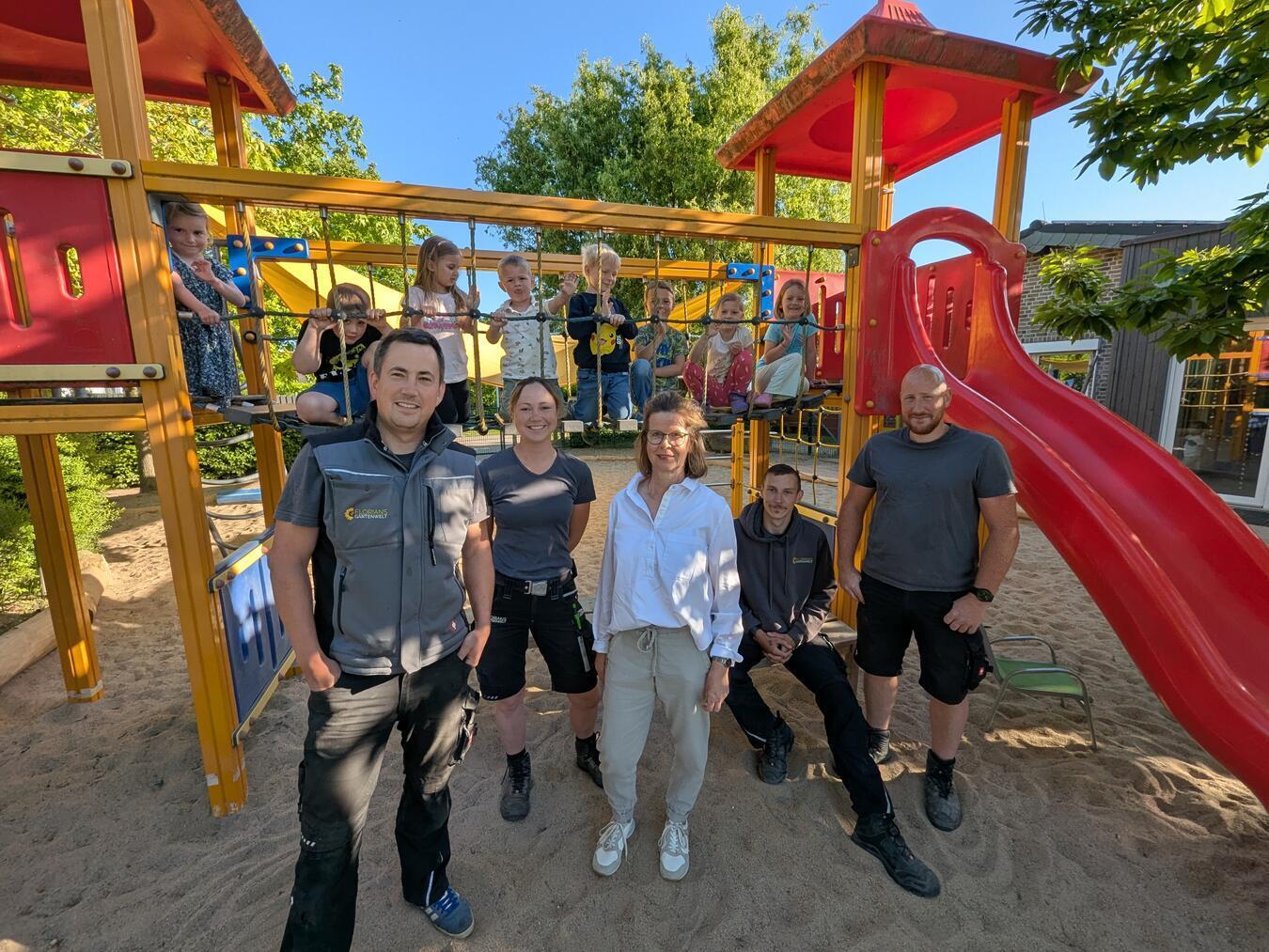 Florian Otto (l.) und sein engagiertes Team gemeinsam mit Birgit Düpont (m.), Leiterin des inklusiven Familienzentrums Hoppetosse, sowie den kleinen Entdeckern beim Probelauf der neuen Außenanlagen. Foto: DRK